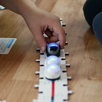 Dzieci bawią się robotami jeżdżąceymi po stole